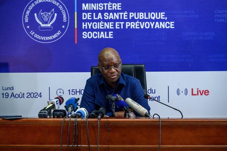Democratic Republic of Congo Health minister Samuel-Roger Kamba sits at a podium with microphones during a press conference